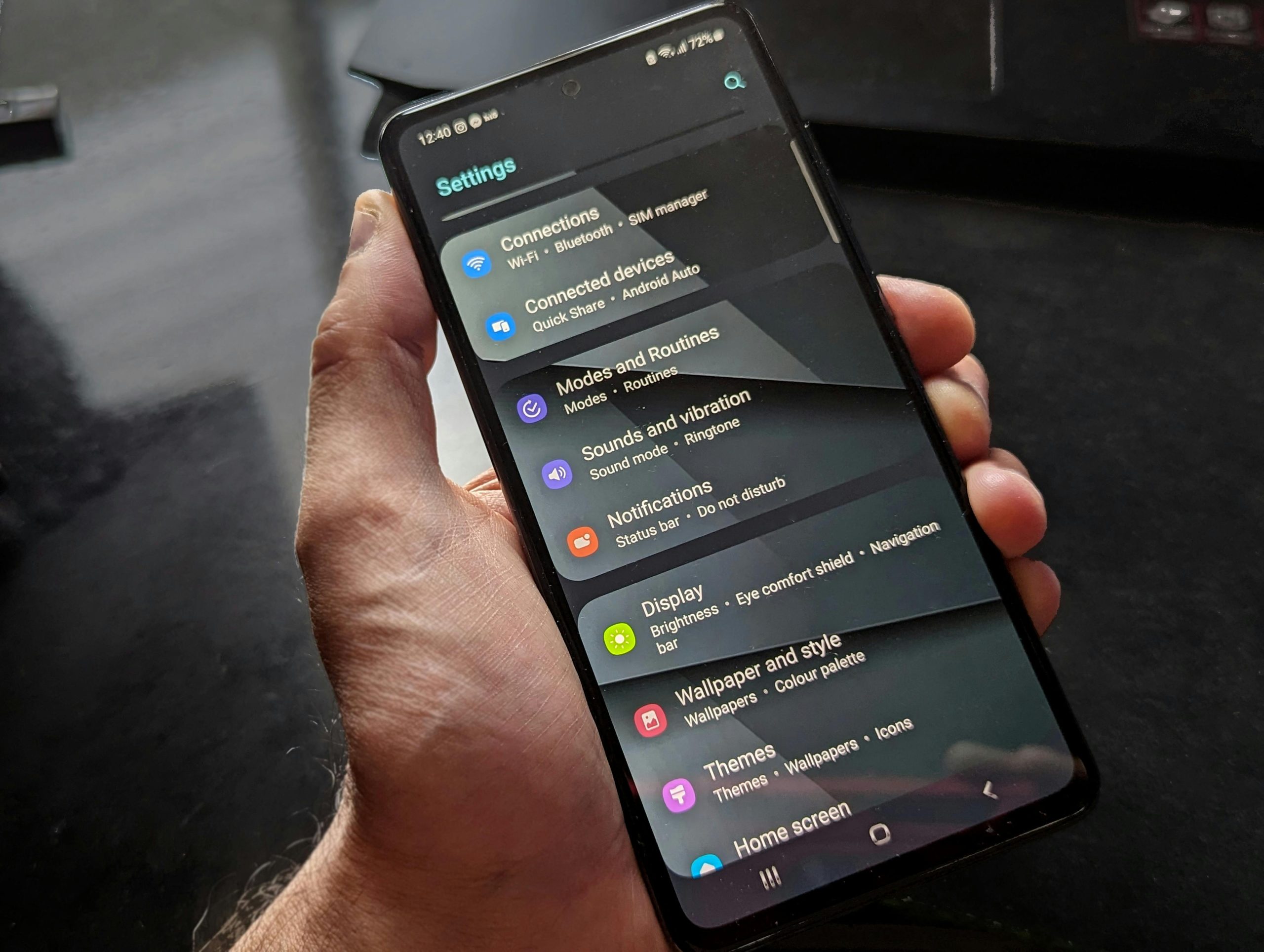 Dłoń trzymająca smartfon z otwartymi ustawieniami systemowymi Android